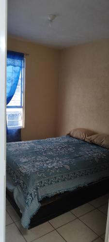 a bedroom with a bed with a blue blanket and a window at Casa Latania in El Salto