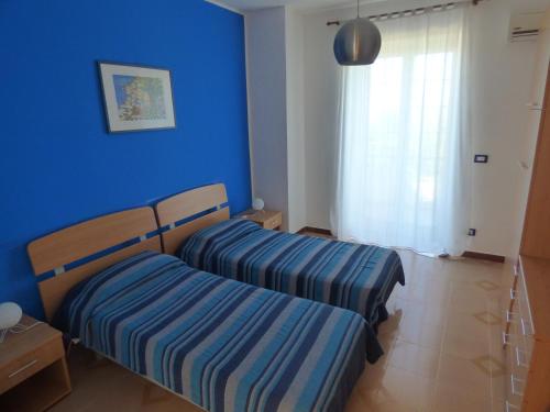2 łóżka w pokoju z niebieską ścianą w obiekcie Villa Maria w mieście Patti