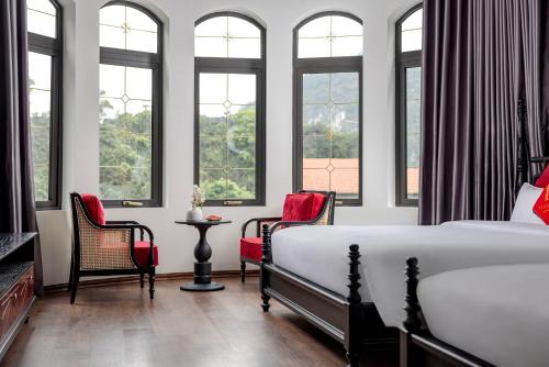 a bedroom with a bed and chairs and windows at Indochine Boutique Hotel Ninh Bình in Ninh Binh