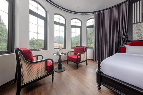a bedroom with a bed and two chairs and a table at Indochine Boutique Hotel Ninh Bình in Ninh Binh