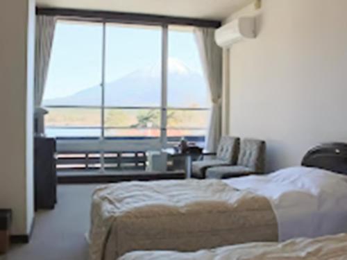 a bedroom with two beds and a couch and a window at Shoji Mount Hotel - Vacation STAY 83000v in Narusawa