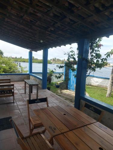 a porch with a wooden table and chairs and the water at Passarinhos Hospedagem in Extremóz