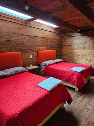Cette chambre dispose de 2 lits rouges et de murs en bois. dans l'établissement cabañas en zacatlan, à Zacatlán