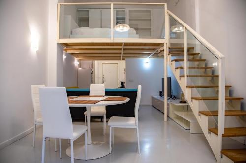 Habitación con mesa, sillas y escalera. en White Loft Salerno en Salerno