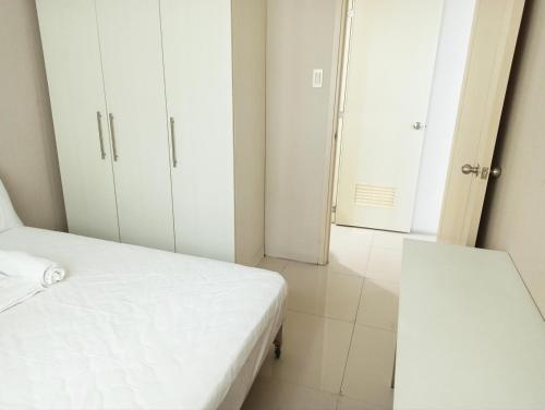 a bedroom with a white bed and a doorway at Minimalist Condotel at SMDC Sea Residences in Manila