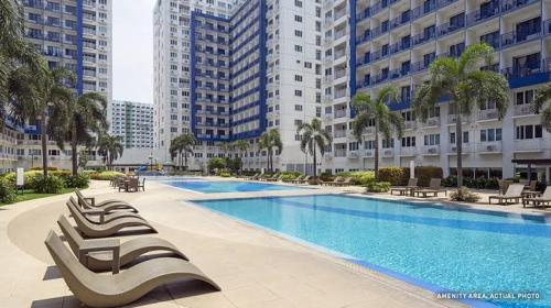 a large swimming pool in a city with tall buildings at Minimalist Condotel at SMDC Sea Residences in Manila
