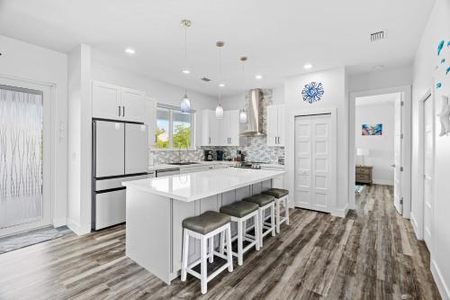 a kitchen with white cabinets and a large island with bar stools at Luna Light ~ Waterfront ~ Pool ~ Dock ~ Views in Marathon