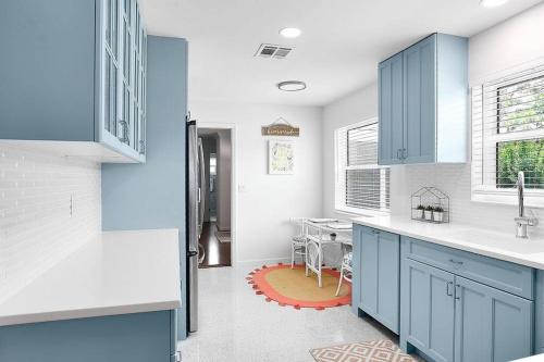 a kitchen with blue cabinets and a dining room at Oasis: Hot tub, fire pit, fun! in Vero Beach