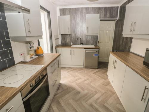 a kitchen with white cabinets and wooden floors at 5 Pontardulais Road in Llanelli