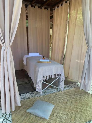 Bett in einem Zimmer mit Vorhängen und einem Tisch in der Unterkunft Hashigute Spa e Hostel in Arraial d'Ajuda