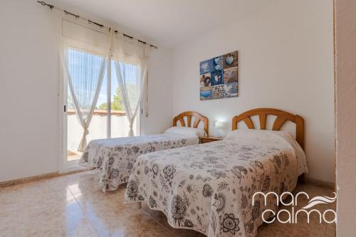 two beds in a room with a window at Villa Dolce Relax by MarCalma in Les tres Cales