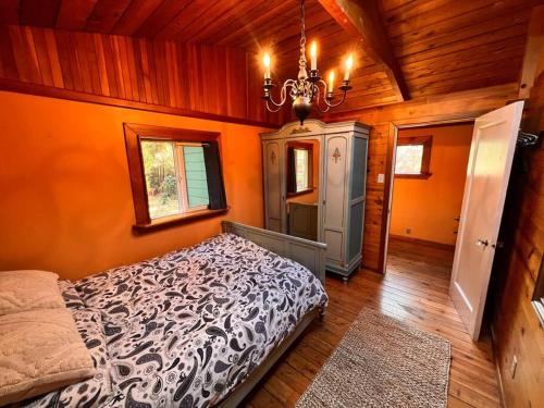 a bedroom with a bed and a chandelier at Nostalgic Downtown Boatbuilder's Cabin - Licensed in Squamish