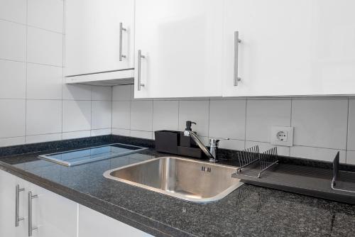 a kitchen with a stainless steel sink and white cabinets at AlohaMundi Castilla V in Seville
