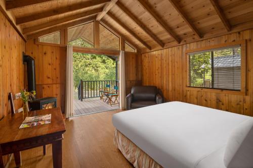 a bedroom with a bed and a desk and a balcony at El Capitan Canyon in Capitan