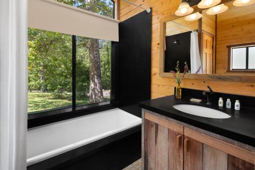 baño con bañera, lavabo y ventana en El Capitan Canyon en Capitan