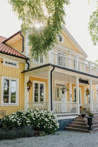 a yellow house with a porch and stairs at Skäftekärr Hotell in Löttorp