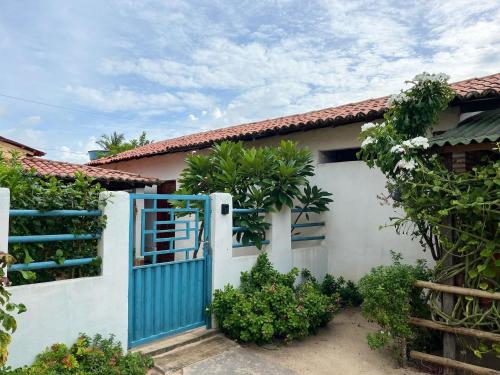 une maison blanche avec un portail bleu et des plantes dans l'établissement Caminho do Mar - Barra Grande (Ótima Localização), à Barra Grande