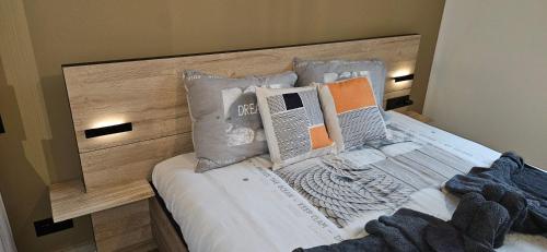 a bed with a wooden headboard and pillows on it at Poppies Flats in Ypres