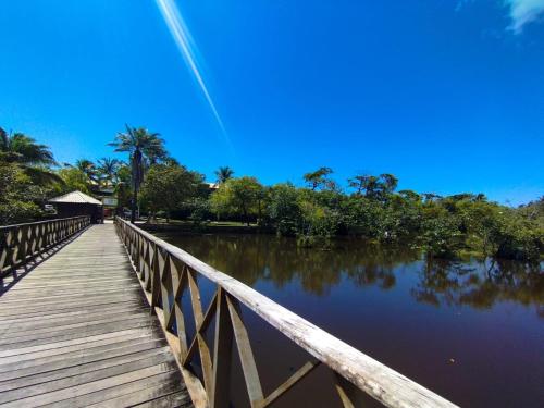 a bridge over a body of water with trees at Pousada Sonho da Lagoa in Praia do Forte