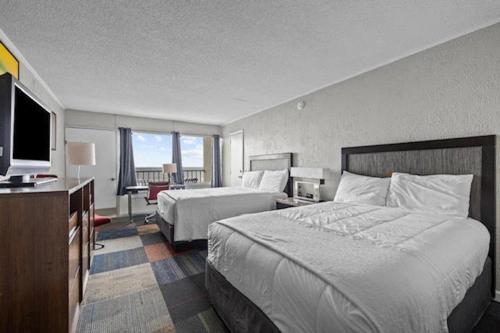 a hotel room with two beds and a flat screen tv at Oasis Hotel in Myrtle Beach