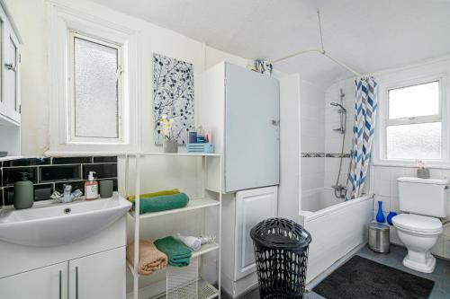 a white bathroom with a sink and a toilet at Stylish Apartment Near Broadway Theatre in Catford