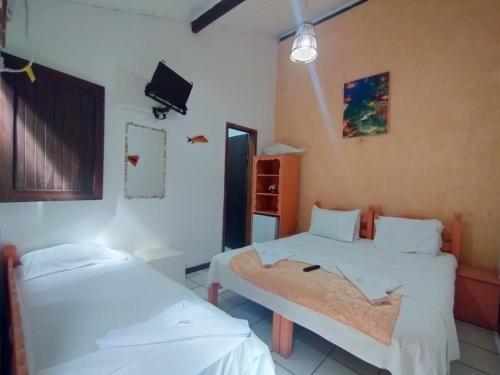 a hospital room with two beds and a tv at Pousada Sonho da Lagoa in Praia do Forte