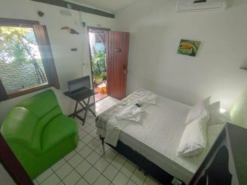 a bedroom with a bed and a green chair at Pousada Sonho da Lagoa in Praia do Forte