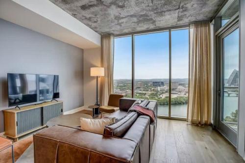 a living room with a couch and large windows at Luxury 2BR Rooftop Pool Austin by Barclé in Austin