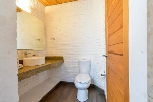 a white bathroom with a toilet and a sink at Hermosa cabaña de descanso en Tlapalpa in Tapalpa