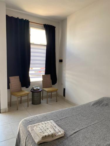 パソ・デ・ロス・リブレスにあるLoft 856のベッドルーム1室(椅子2脚、ベッド1台、窓付)