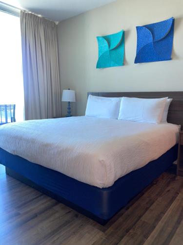 a bedroom with a large bed with blue pillows at South Beach Biloxi Hotel & Suites in Biloxi