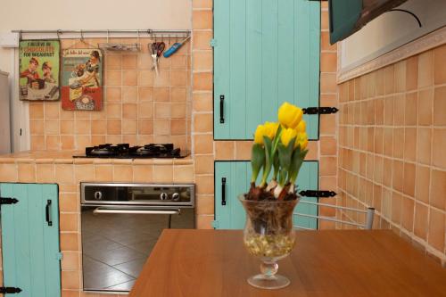 a vase with yellow flowers on a table in a kitchen at la coccinella in Marina di Pisa