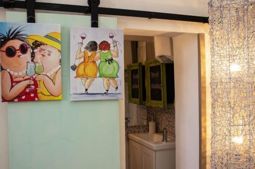 a bathroom with three pictures of women on the wall at la coccinella in Marina di Pisa