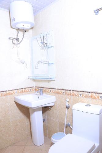 La salle de bains est pourvue de toilettes blanches et d'un lavabo. dans l'établissement Very secure apartment Bole Addis Enyi Real Estate, à Addis-Abeba