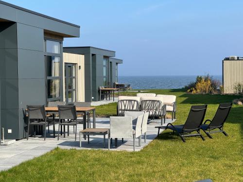 a patio with chairs and tables and the ocean at Enkhuizer Strand Chalet WellenZeit Haus Nr 260 in Enkhuizen