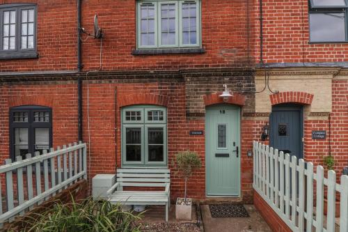 a brick house with a blue door and a white fence at Holmleigh, Aldeburgh in Aldeburgh