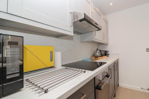 a kitchen with white cabinets and a yellow appliance at Holmleigh, Aldeburgh in Aldeburgh