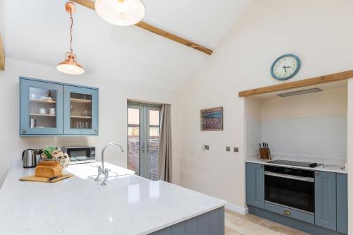 a kitchen with a counter top and a clock on the wall at Snipe Meadow Barn by Big Skies Estates in Swafield