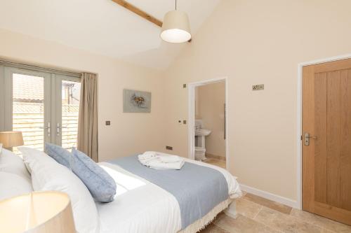 a bedroom with a bed with white sheets and blue pillows at Snipe Meadow Barn by Big Skies Estates in Swafield
