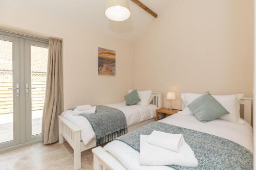 two beds in a room with a window at Snipe Meadow Barn by Big Skies Estates in Swafield