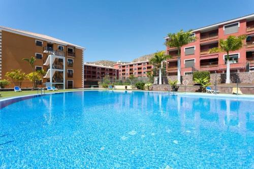 a large blue swimming pool in front of some buildings at Alquilaencanarias El Palm Mar in Palm-mar