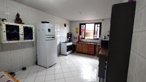 a kitchen with a white refrigerator and a white tile floor at Mandallah Hostel in Joinville