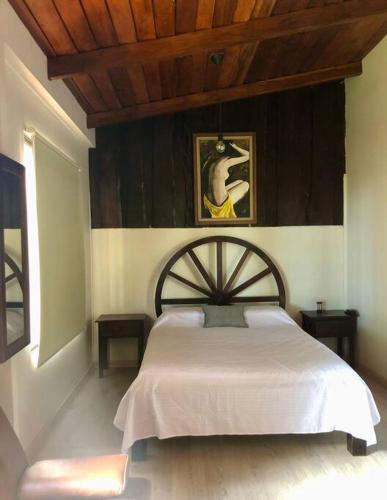 um quarto com uma cama branca e um tecto de madeira em Cabaña Sabana Redonda, Poás em Poás