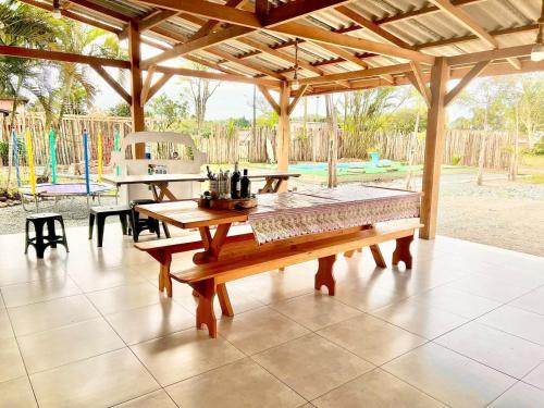 un patio con una mesa de madera y un parque infantil en Recanto Monte Trigo, en São Francisco do Sul