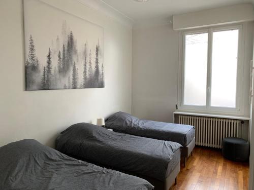 Paris Apartment 5-minute walk to tube station في ليه ليلاس: غرفة نوم بسريرين وصورة على الحائط