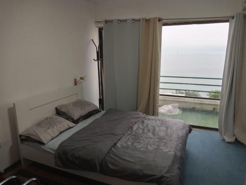 a bedroom with a bed and a large window at נוף הכנרת in Tiberias