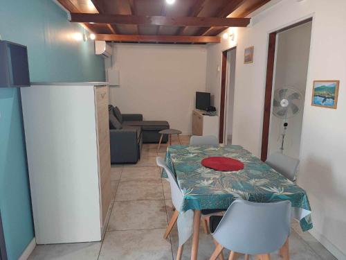 a living room with a table and chairs and a kitchen at Ti Kaz Fond de Puits in Saint-Philippe