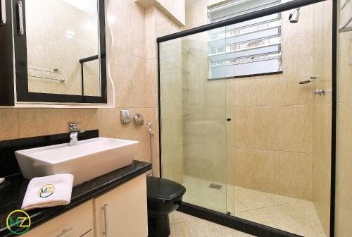 a bathroom with a sink and a glass shower at Amplo 2 quartos na praia do Leme para 7 pessoas in Rio de Janeiro