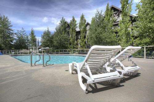 two white chairs sitting next to a swimming pool at The Aspens on Blackcomb in Whistler