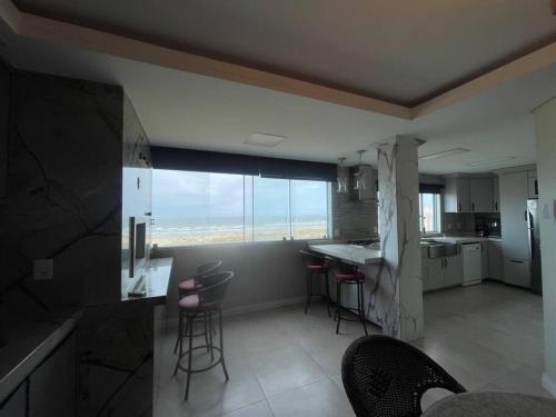 uma cozinha com uma grande janela e cadeiras em Vista para o Mar em Laguna